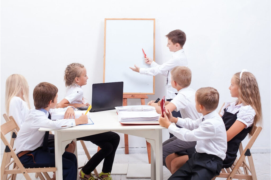 Image of a group of children imitating a board room meeting. 